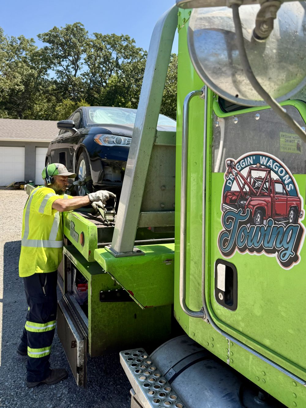 Draggin' Wagons Towing crew member securing a load with a ratchet strap