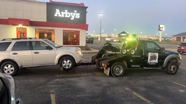 Draggin' Wagons Towing wrecker hooking up a vehicle at night